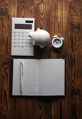 Wall Mural - Calculator, notepad, piggy bank and alarm clock on a wooden background. Business concept. Flat lay