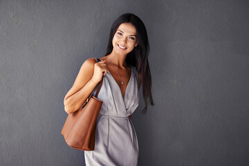 Wall Mural - Studio, portrait and handbag with fashion, model and accessories with dress and joy. Woman, face and smile with confidence, beauty and happiness with purse and style isolated on gray wall background