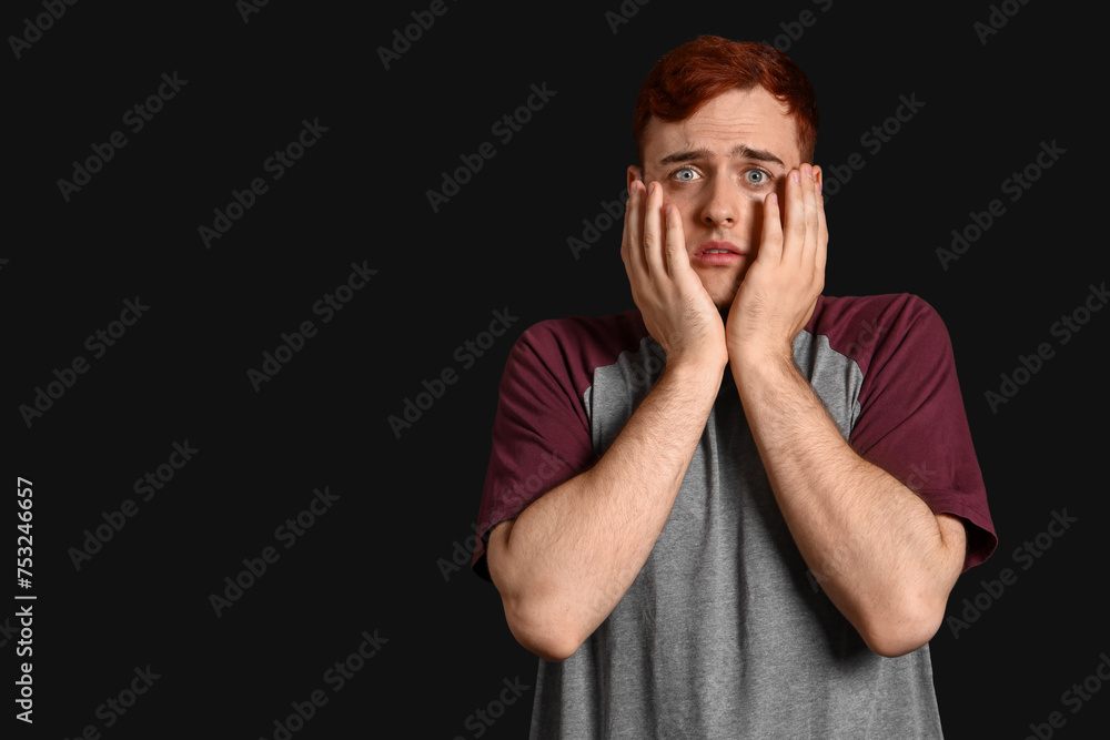 Fearful young man on black background