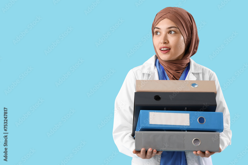 Female Muslim doctor with folders on blue background