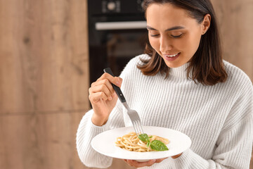 Poster - Young woman with tasty pasta in kitchen, closeup