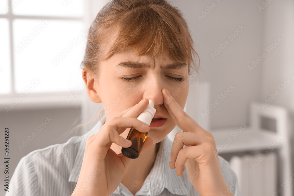 Ill young businesswoman using nasal drops in office, closeup