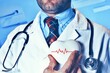 World Hypertension Day. Bearded doctor holds a white heart with a heartbeat chart, a symbol of high blood pressure.