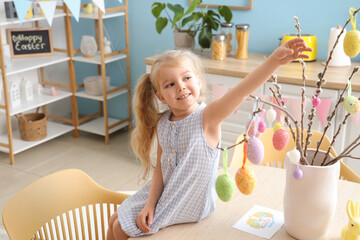 Wall Mural - Cute little girl decorating willow branches with Easter eggs at home