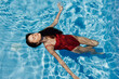 © SHOTPRIME STUDIO - Happy woman swimming in the pool in red swimsuit with loose long hair relaxed in the sunshine, skin protection with sunscreen, concept of relaxing on vacation in tropical climate, lifestyle.