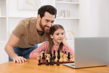 Poster - Father teaching his daughter to play chess following online lesson at home