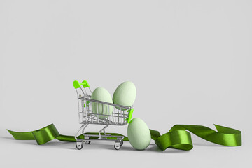 Wall Mural - Small shopping cart with Easter eggs and ribbon on white background