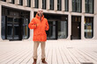 young positive man 30-35 years old man in bright orange jacket with hood on street of Berlin, Youth Culture and Stereotypes, younger generation, Leisure Urban lifestyle, outdoor activities