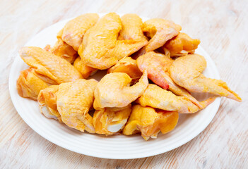 Wall Mural - Close up of raw yellow chicken wings on wooden background