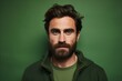 Portrait of a handsome man with a beard on a green background.