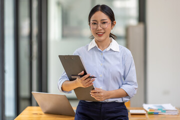 Boring young business Asian woman holding document file and looking at camera stand on a studio shot white background.