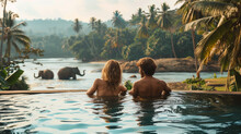 Couple Watching The Sunset In An Infinity Pool On A Luxury Vacation, Man And Woman Watching The Sunset On The Edge Of A Pool In Sri Lanka With Elephants In The Background