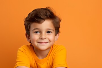 Portrait of a smiling little boy looking at camera over orange background