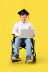 Canvas Print - Male graduate in wheelchair with laptop on yellow background