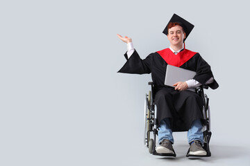 Canvas Print - Male graduate in wheelchair with laptop showing something on light background