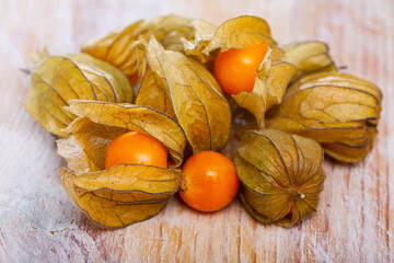 Wall Mural - Yellow ripe physalis fruit (Physalis peruviana) on wooden background, raw fruits