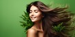 Portrait of a brunette girl with long healthy hair blowing in the wind with medicinal herbs and leaves on a green background, banner with copy space. concept of natural cosmetics for hair and body.