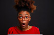 Portrait of stunned gen z African American girl on black studio background shocked by sale offer or discount online on laptop. Amazed young black woman surprised by unexpected news on computer