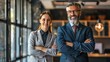 © Nisa - Business man and woman standing with arms crossed in the office Generative Ai