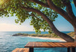 Serene tropical beach view with wooden platform under a shady tree overlooking a tranquil blue sea.