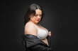 A woman in a black jacket wears a white bra. The concept of confidence and empowerment as a woman proudly shows off her bra. A black jacket adds sophistication. Fat woman.