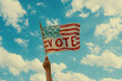 A person waving a USA stars and stripes election Vote flag under a sunny sky