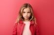 Portrait of a cute little girl in a pink jacket on a red background.
