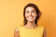 Portrait of beautiful smiling young woman looking at camera over yellow background