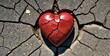 A red stone heart smashed in a cracked concrete ground as a symbol for a broken heart and lovesickness -Generative AI
