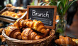 Freshly baked croissants in a wicker basket with a Brunch signboard in a cozy cafe atmosphere, inviting for a weekend gourmet experience