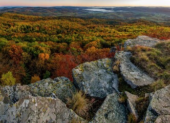 Wall Mural - Stone top of the hill, autumn colored trees. Scenic autumn morning sunrise on Sitno hill over Banska Stiavnica in Slovakia, colorful leaves of trees in forest on the mountains.