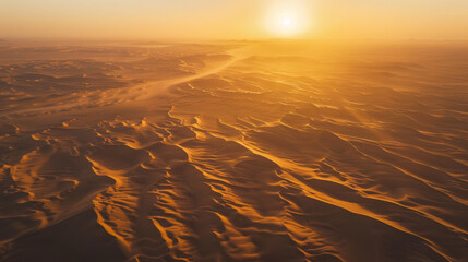 An aerial view of a vast desert at sunset, the landscape bathed in warm golden hues, long shadows cast by dunes, creating a serene and majestic atmosphere.