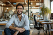 © Ishra - Portrait of a smiling businessman sitting inside minimal workplace, professional confident looking young man seated in office, Business man working in modern office room, The CEO sits in office chair