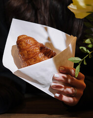 Wall Mural - Woman holding a croissant in her hand in coffee shop