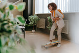 Fototapeta Tęcza - Elegant businesswoman in casual clothes riding on skateboard