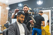 Professional barber styling his Indian client hair with a dryer in a barbershop. High quality photo