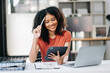 © Nuttapong punna - Confident woman with a smile standing holding notepad and tablet at the modern office.