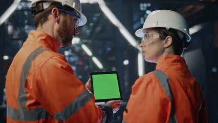 Canvas Print - Factory boss showing green screen tablet to woman employee in facility close up.
