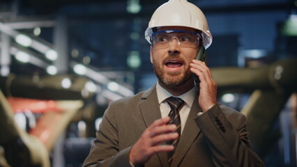 Canvas Print - Factory engineer speaking cellphone at production in protective helmet close up.