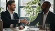 © Yuliia - Two diverse multiracial businessmen signing document agreement shaking hands success business deal. Multiethnic men partners in office meeting handshake satisfied agree sign loan investment contract