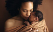 Close up of young afro american black woman with closed eyes hugging newborn sleeping wrapped in a blanket for comfort over brown studio background. Concept of love in motherhood and care of childhood