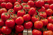 © ADDICTIVE STOCK - Close-up view of ripe red tomatoes with fresh green stalks, neatly arranged in a wooden crate at a vegetable stall