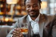 © Pinklife - Close-up of a smiling gentleman in a suit offering a whiskey glass to the viewer, emphasizing satisfaction