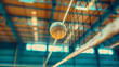 Closeup of the white volleyball sport ball flying in the air towards the net in the arena interior. Nobody indoors, empty stadium for a competition event. 