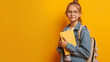Garota com mochila pronto para ir a escola sorrindo isolado no fundo amarelo