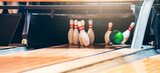 Fototapeta  - Bowling ball hits pins at end of glossy wooden bowling alley. 