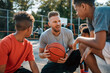 © matimix - Young Basketball Coach With Happy Kids in Training. Trainer Explaining to the Team the Game Rules and Match Strategy. Boys Compete in School Basketball Tournament