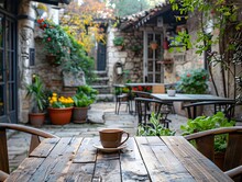 Cafe In A Stone House With Wooden Tables And Greenery, To Convey A Sense Of Relaxation And Enjoyment In A Traditional Setting
