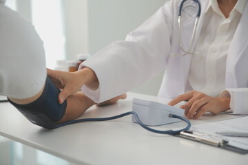 Wall Mural - Male doctor uses a blood pressure monitor to check the body pressure and pulse of the patients who come to the hospital for check-ups, Medical treatment and health care concept.