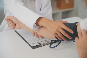 Wall Mural - Male doctor uses a blood pressure monitor to check the body pressure and pulse of the patients who come to the hospital for check-ups, Medical treatment and health care concept.